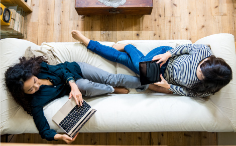 two girls using laptops on the couch