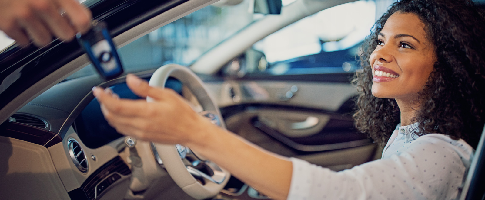 A young, happy woman accepting keys to new car
