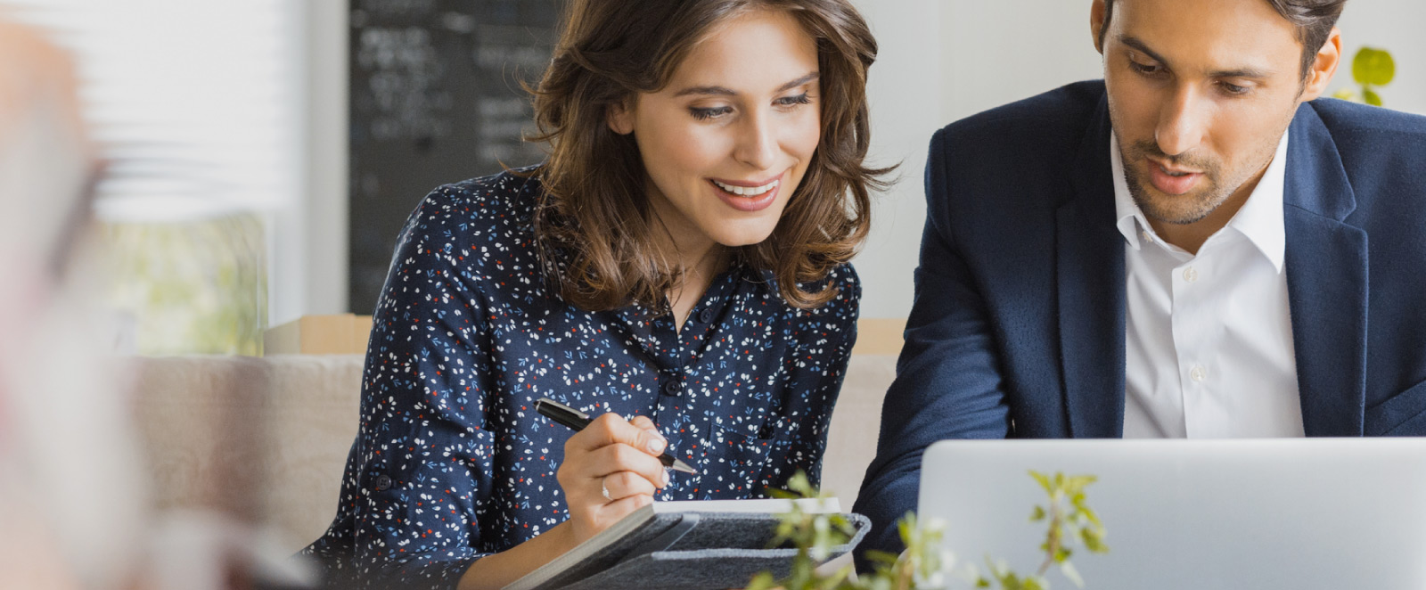 Two people looking at a notebook and laptop