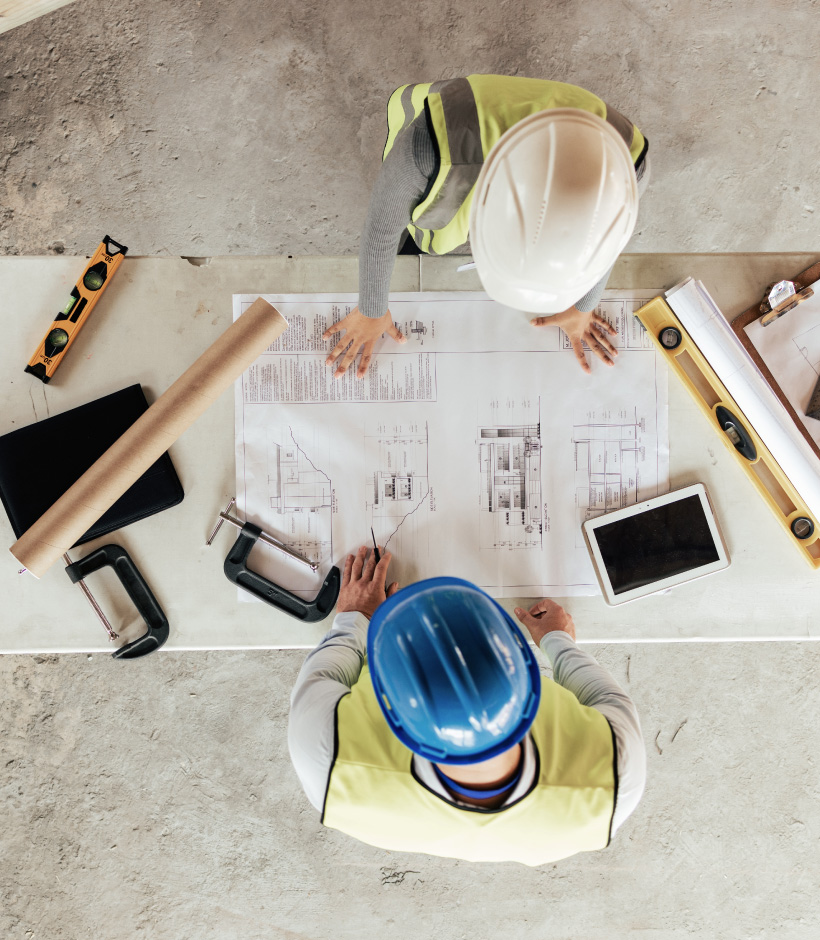 two people looking at blue prints in hard hat