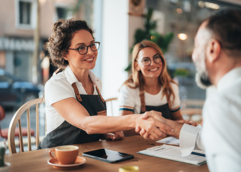 shaking hands over a table with coffee