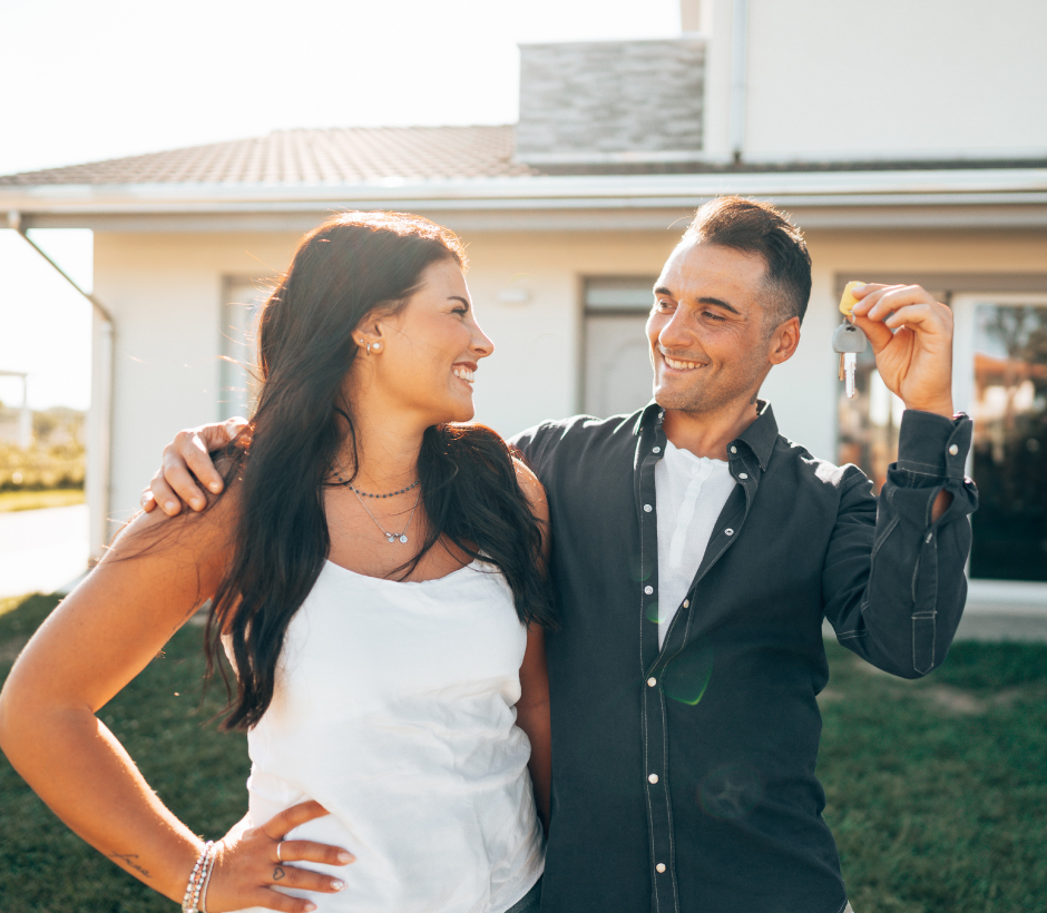 couple holding keys in front of home