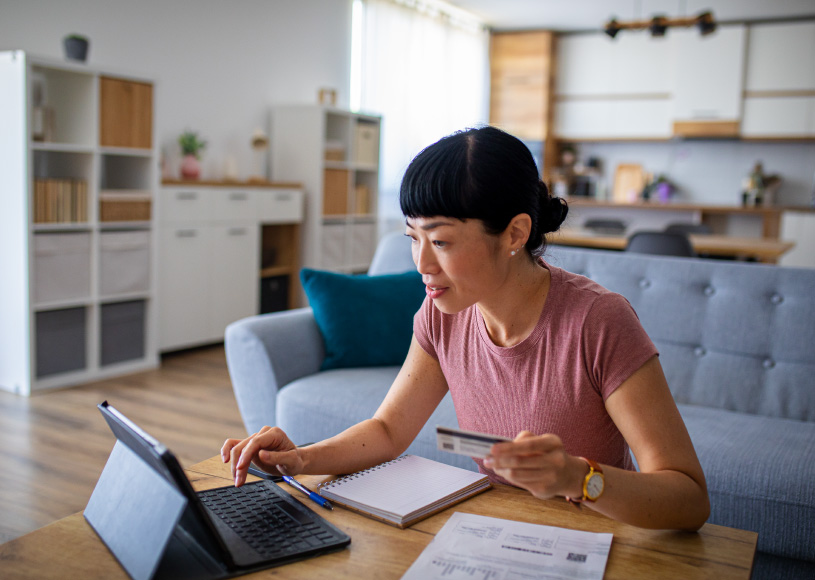 person holding card and looking at laptop