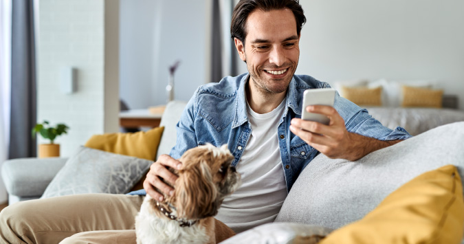 person petting dog with phone in hand