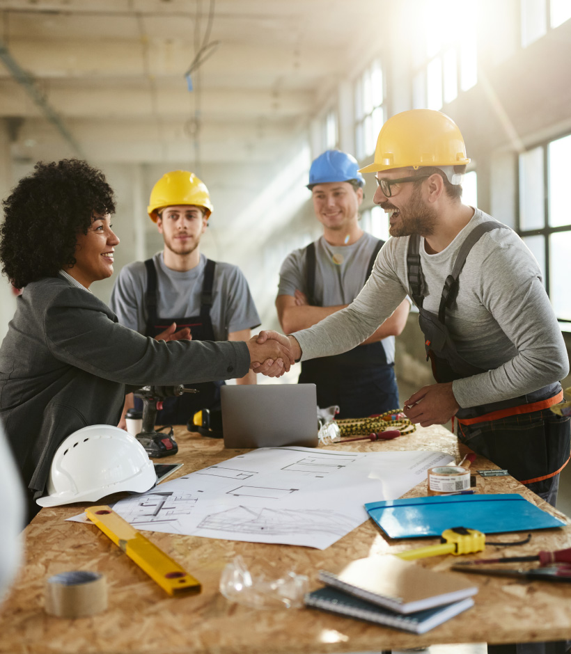 business people shaking hands over blueprint