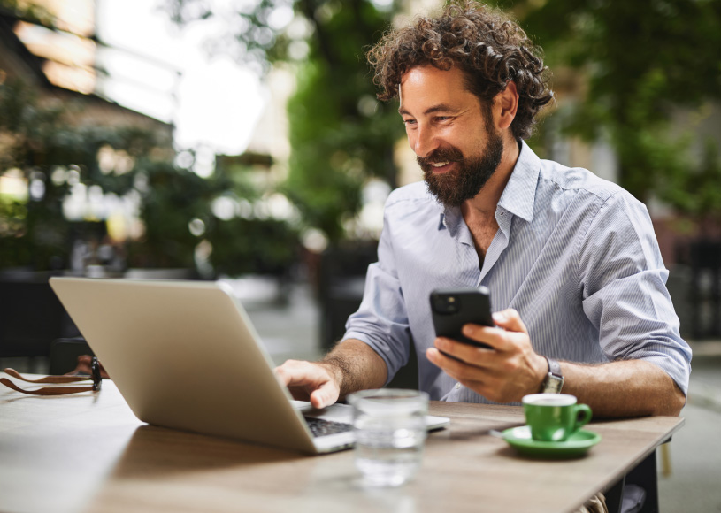 person looking at laptop and holding phone