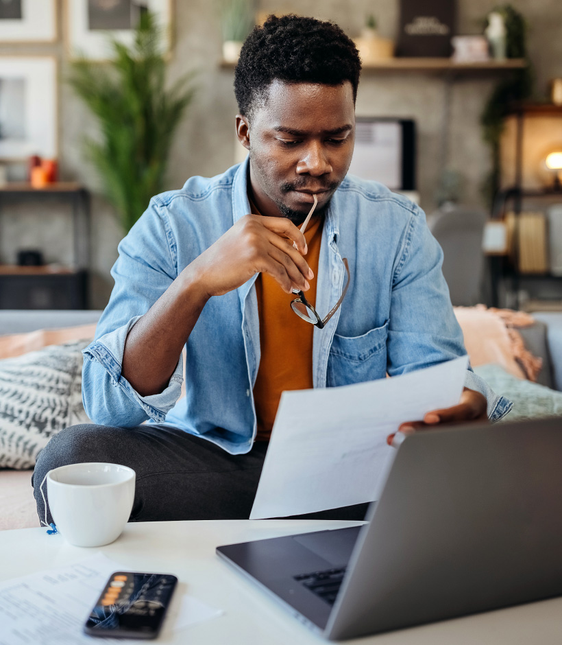 person looking at paperwork with laptop and calculator nearby