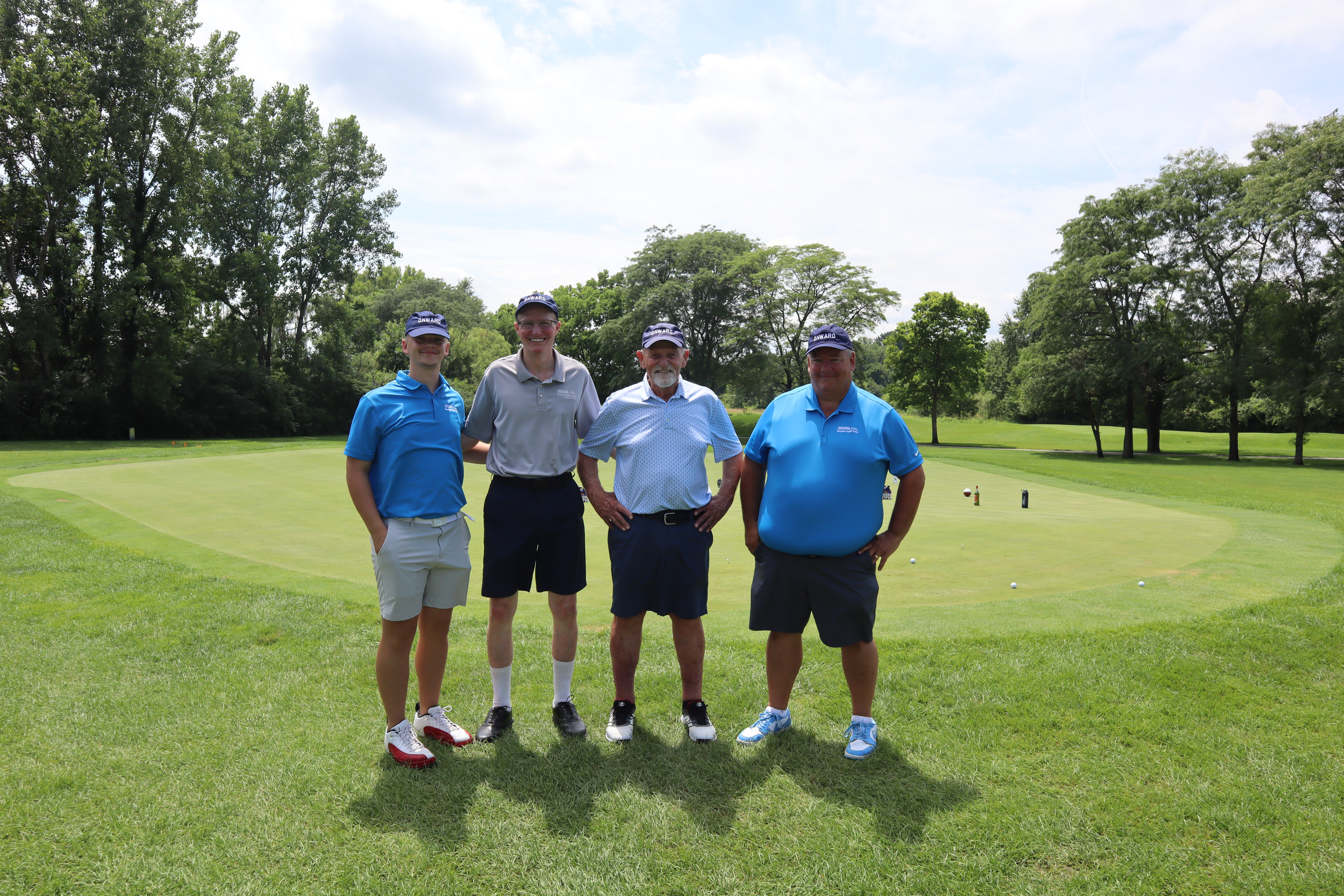 4 golfers in front of golf green