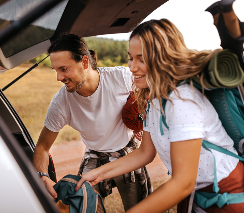 couple grabbing camping gear from the back of the car